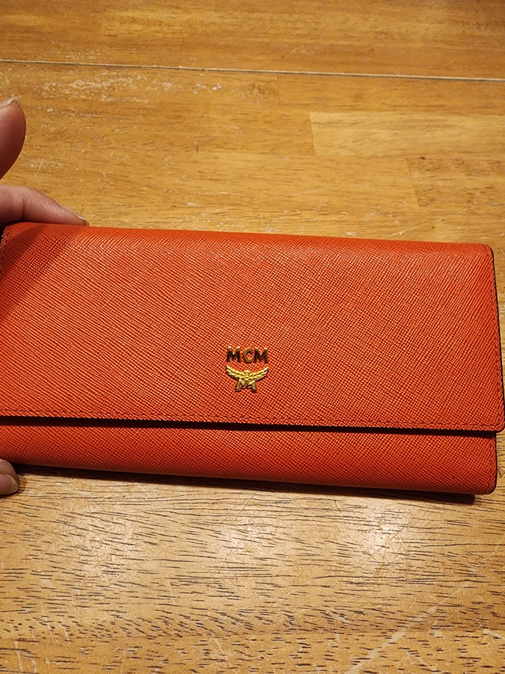 orange MCM leather wallet featuring gold-tone hardware